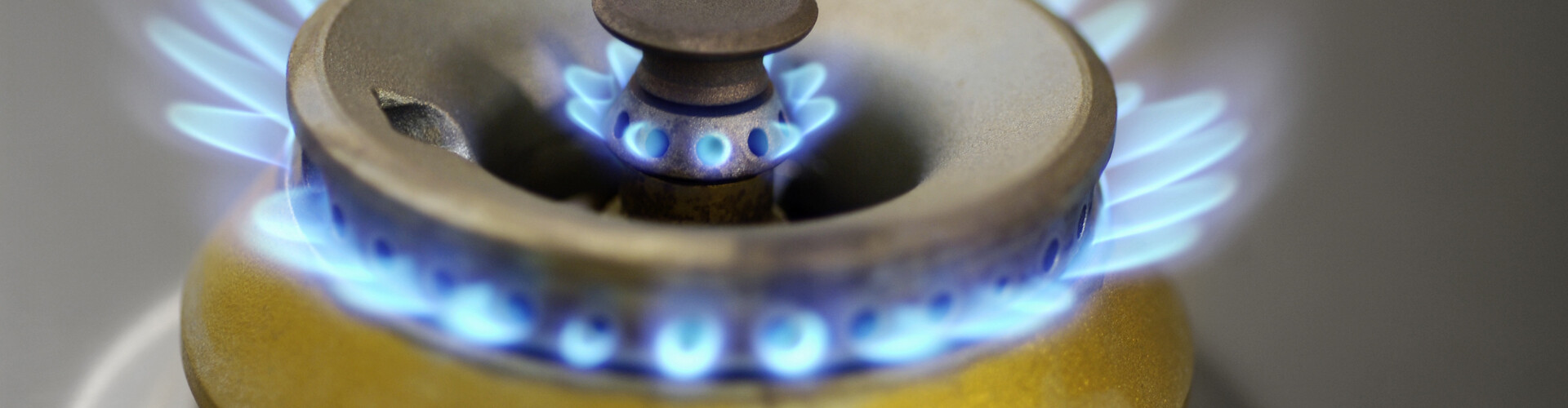 In der Nahaufnahme flimmern blaue Flammen auf dem Gasherd.