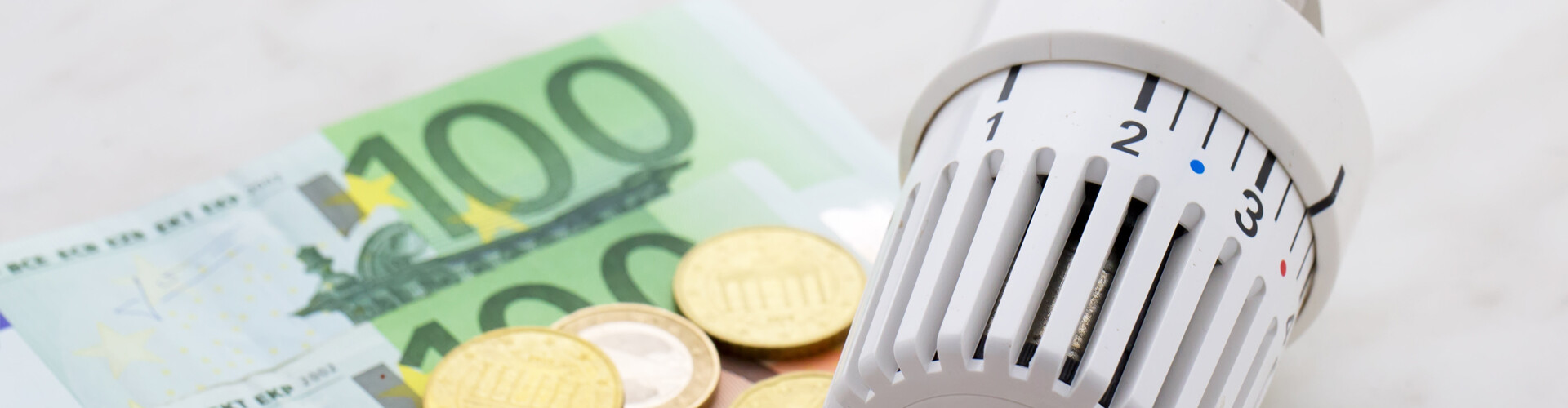 Neben dem Temperaturregler einer Heizung liegen zwei Hundert-Euro-Scheine und etwas Kleingeld.
