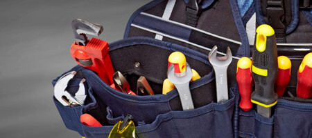 Eine geöffnete Handwerkertasche mit einer Vielzahl an Werkzeugen.
