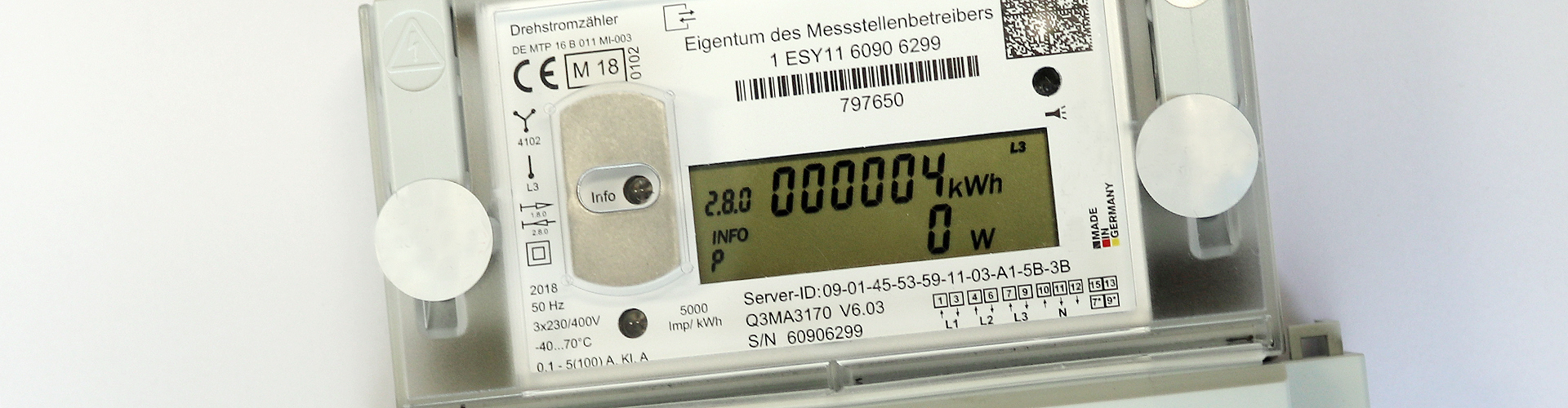 Auf einem digitalen Zähler ist ein Display zu sehen, auf dem 4 Kilowattstunden angezeigt werden. Der Zähler ist weiß. Neben der Aufschrift "Eigentum des Messstellenbetreibers" sind zudem zahlreiche technische Angaben auf dem Gerät vermerkt. 