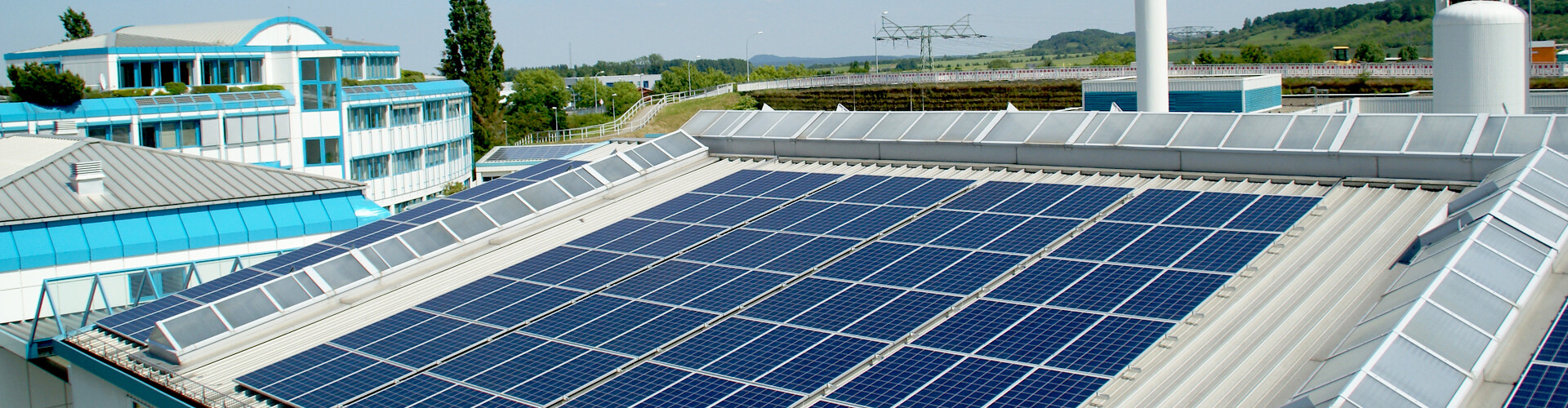 Ein weißes Dach ist mit zahlreichen Photovoltaikmodulen bedeckt. Im Hintergrund ist das Verwaltungsgebäude der Stadtwerke Wernigerode GmbH zu sehen. 